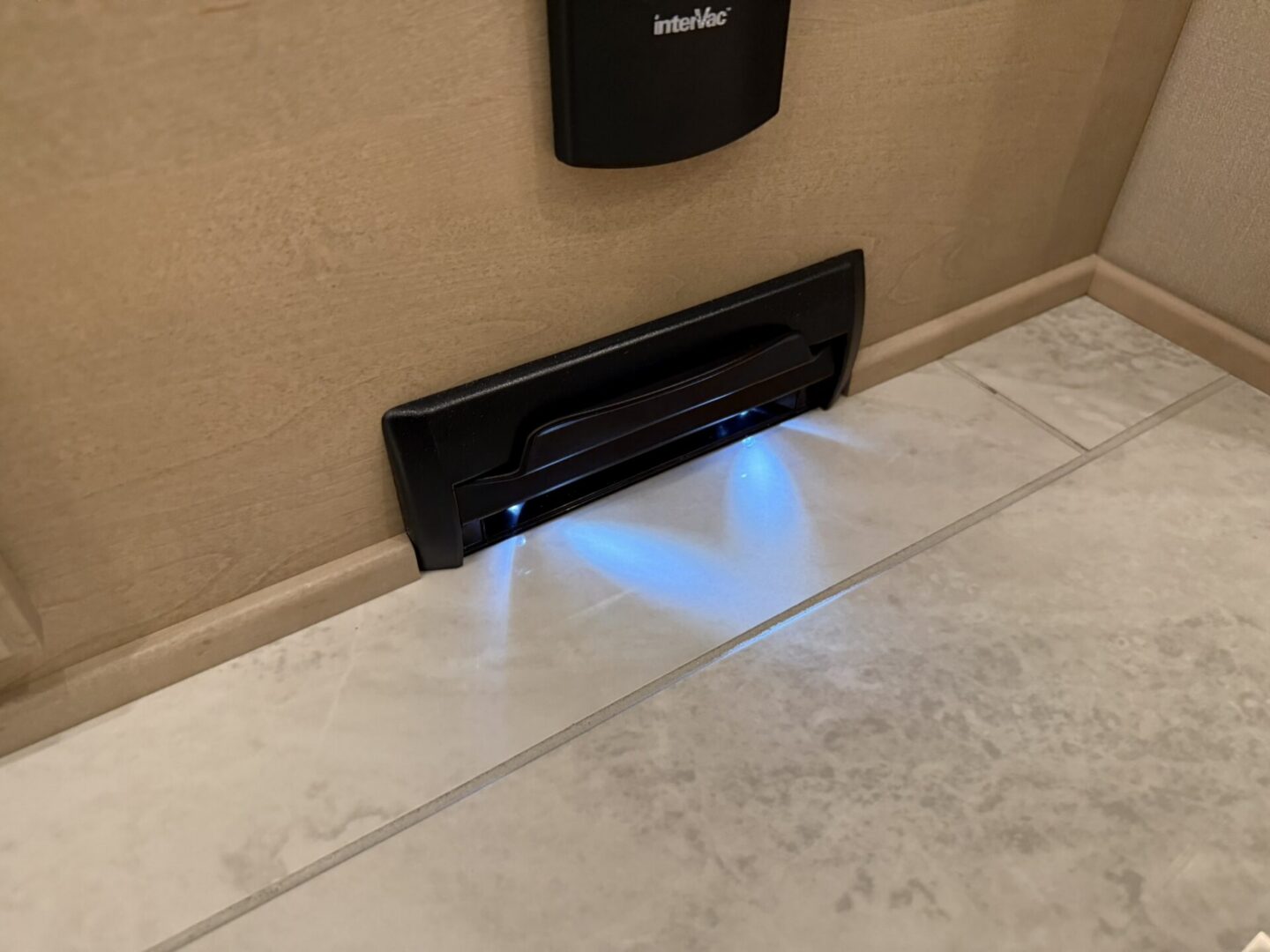 LED lighted vacuum inlet on tiled floor.