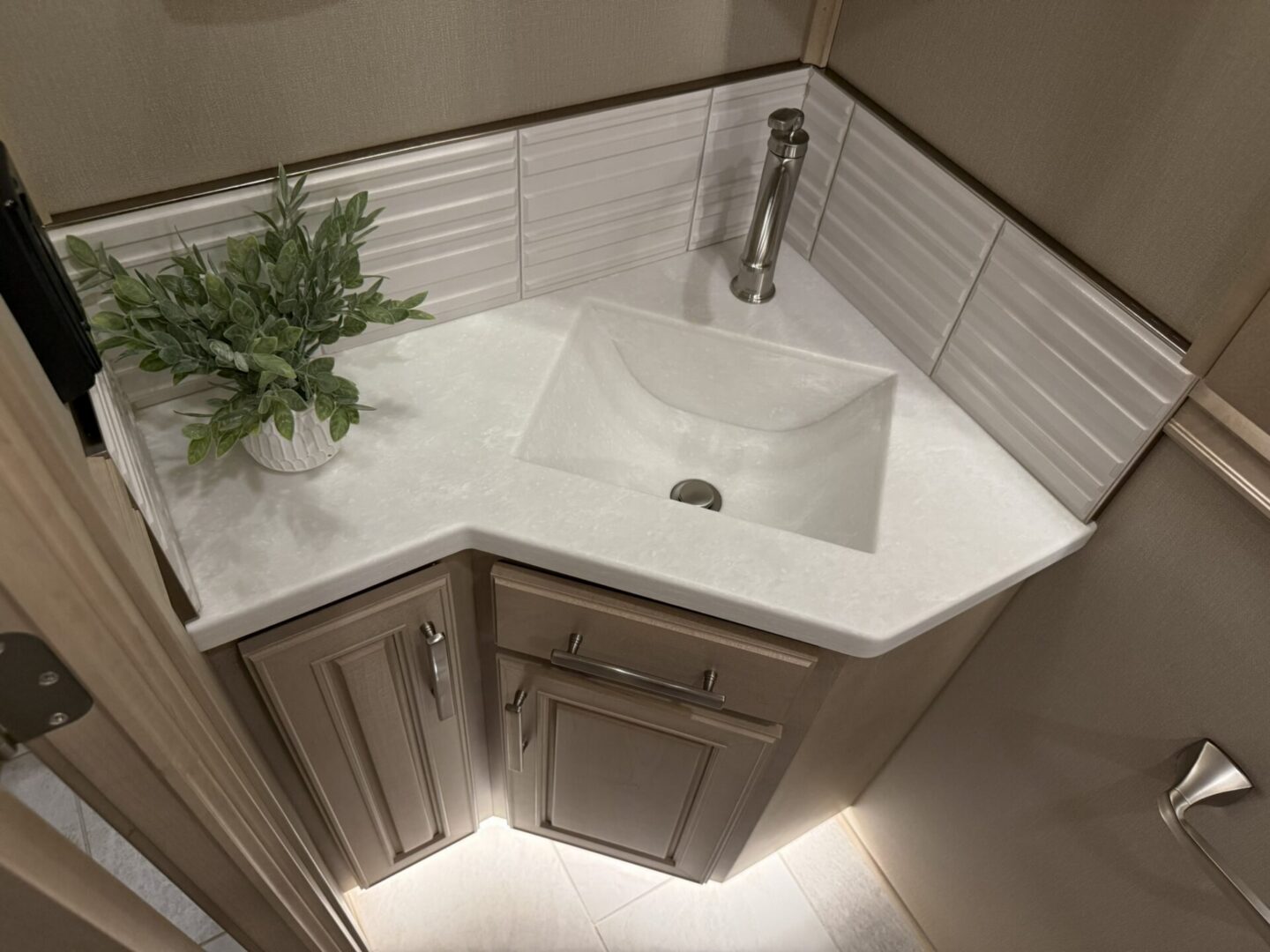 Modern corner bathroom sink with plant.