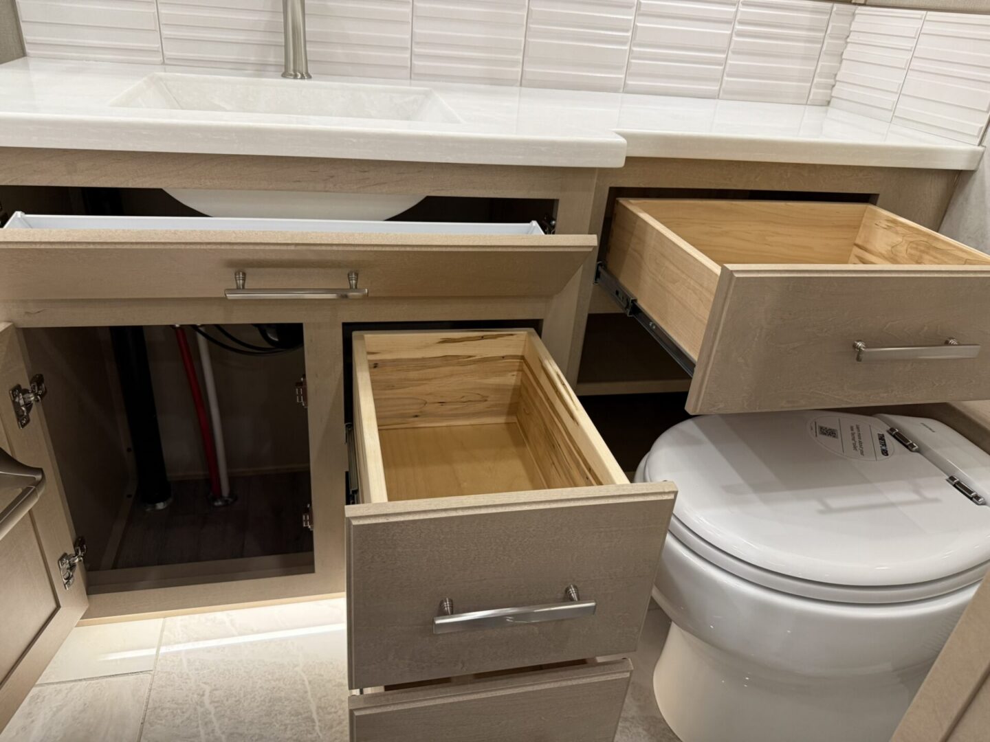 Bathroom vanity with open drawers and toilet.