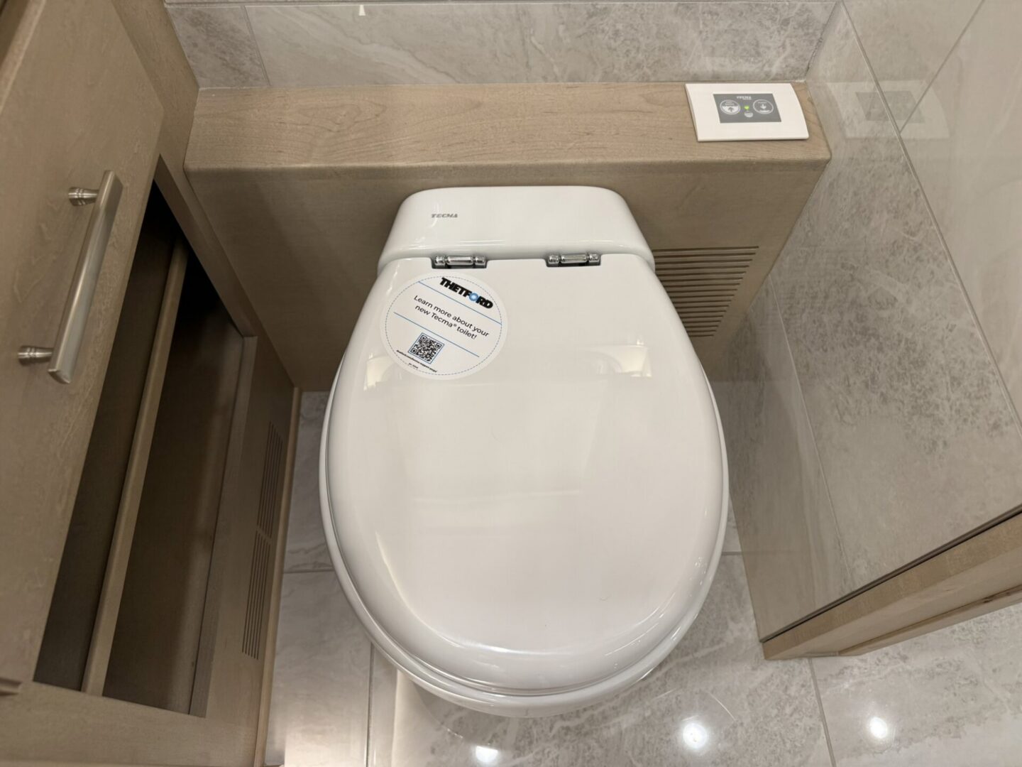 Modern toilet with control panel nearby.